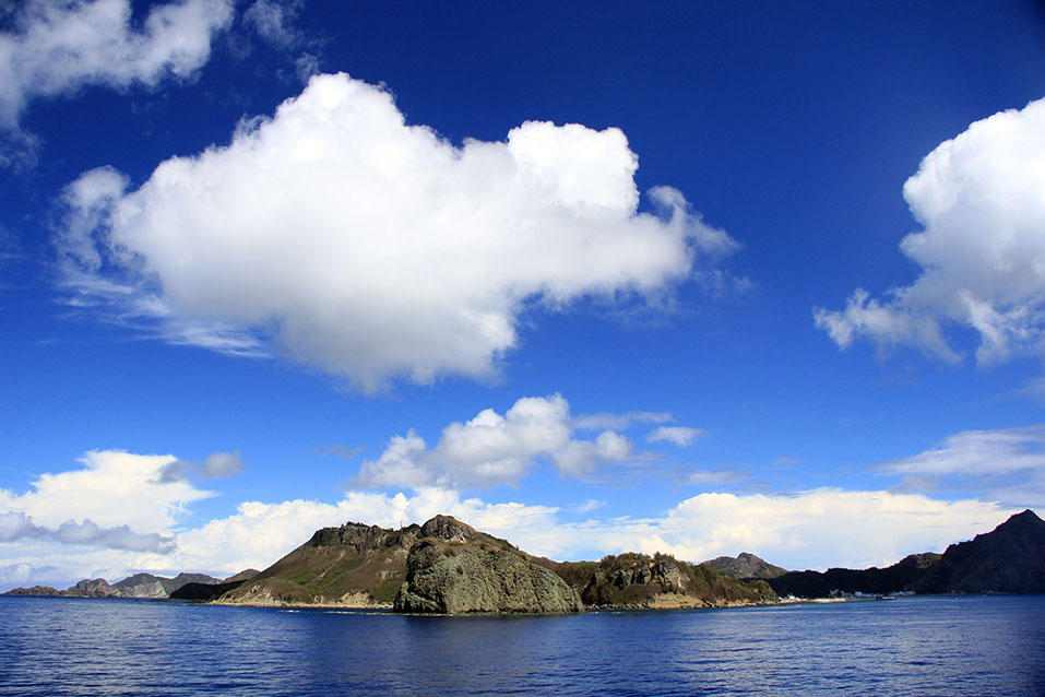 The silhouettes of the islands begin to appear on the horizon.