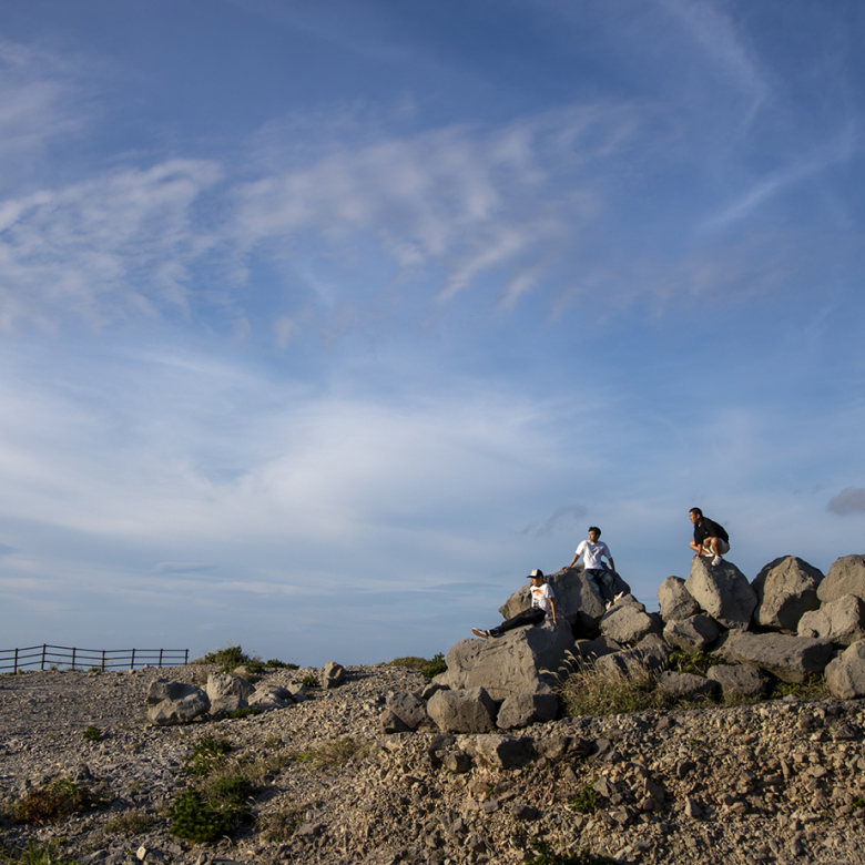 岩の上に座り景色を眺める3人