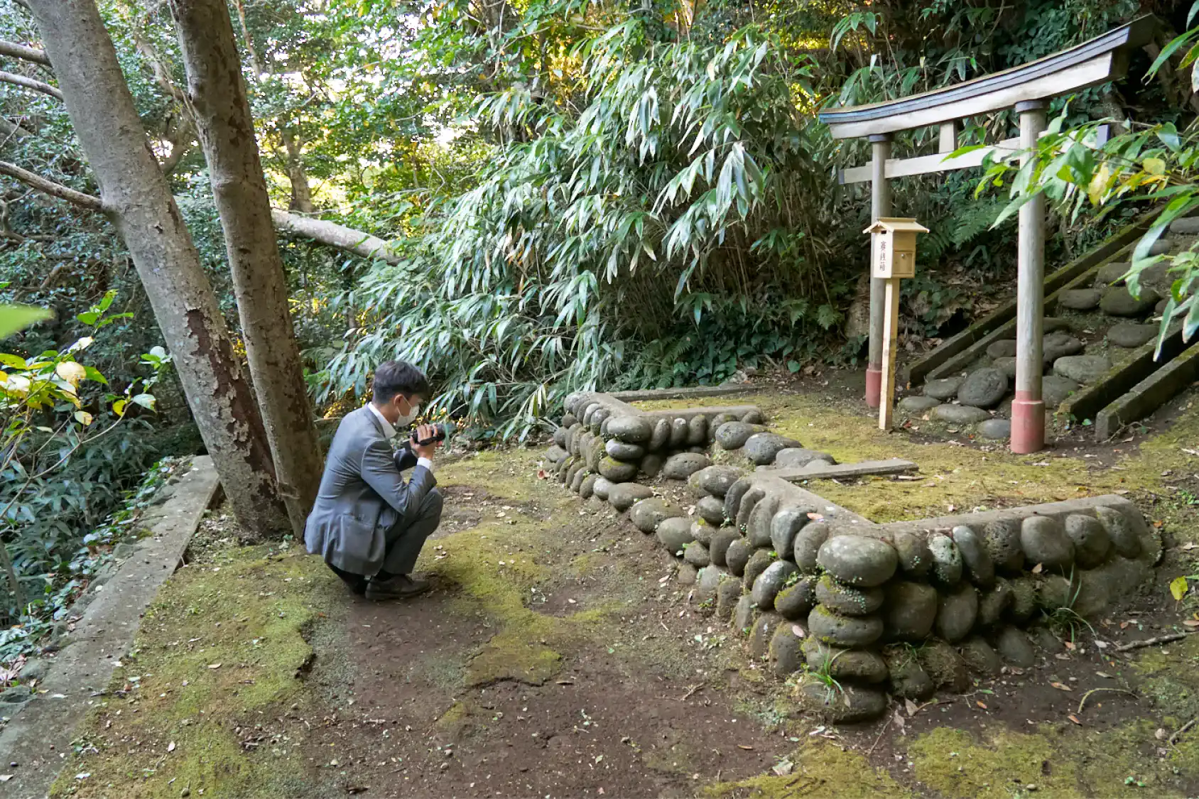 大山小山神社の鳥居の前で屈むスーツさん