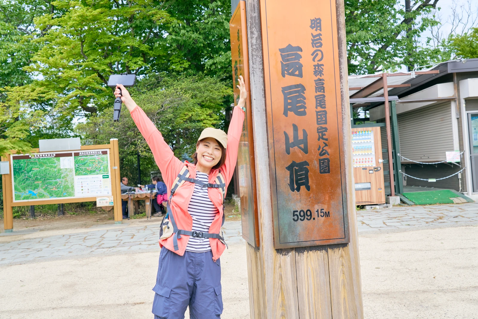 山頂の標高599.15Mを知らせる看板の前でバンザイするかほさん