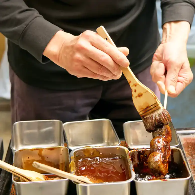 こなれた手つきでお団子にゴマだれを塗る店員さん