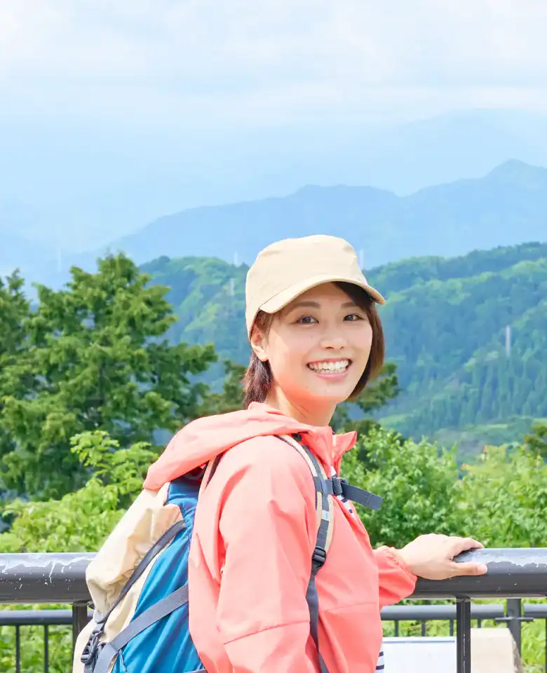 高尾山山頂の風景をバックに微笑むかほさん