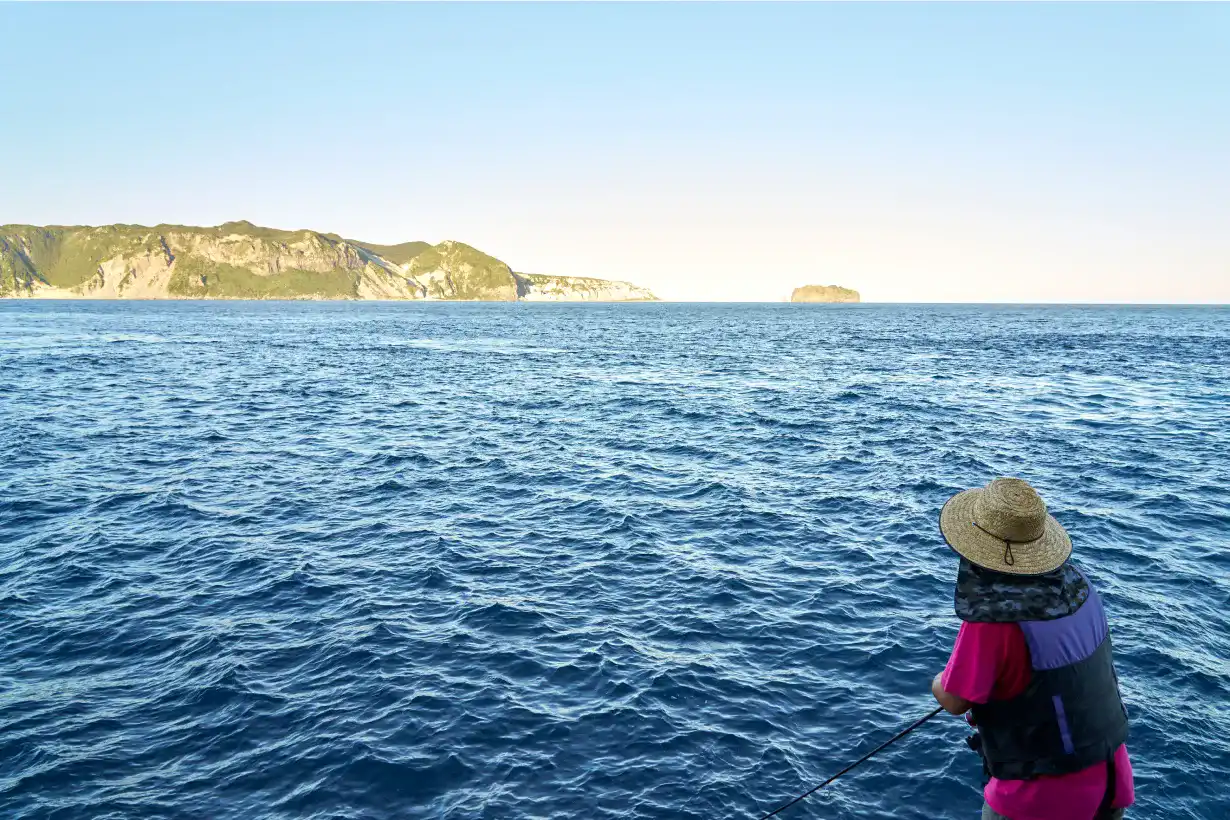 新島の断崖を奥に望みながら釣りをするとくさん