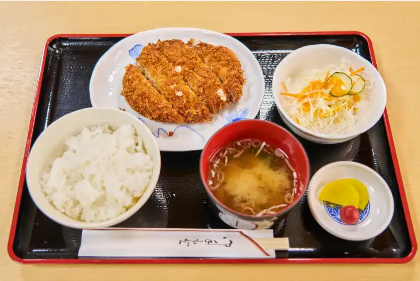 美味しそうなまぐろメンチカツ定食。メンチカツに白ご飯とお味噌汁、サラダと漬物。