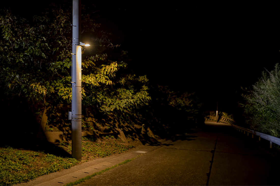電球のような暖色の街灯が1つだけある道路